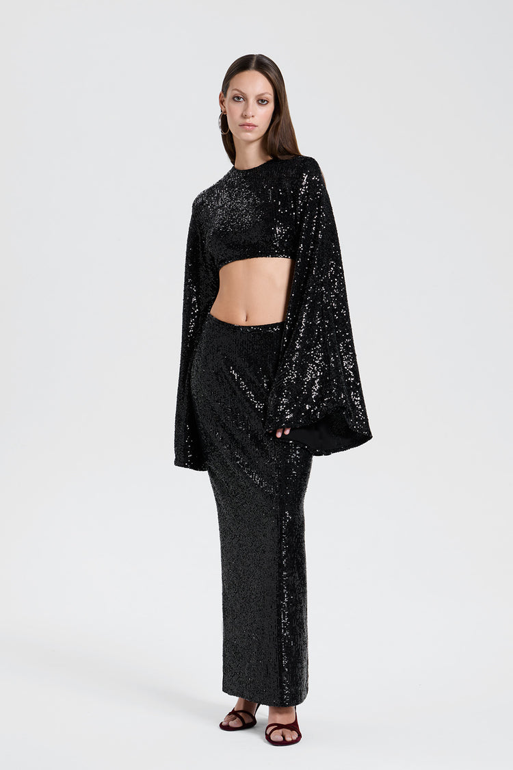 Woman wearing a black sequin two piece set skirt and crop top outfit  on a white background